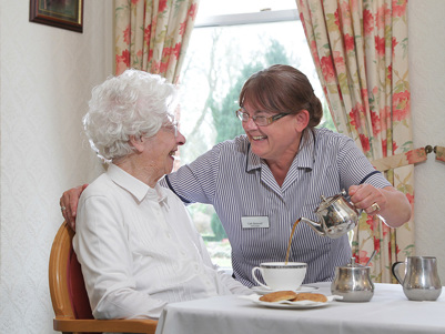 Resident being served tea in the dining room